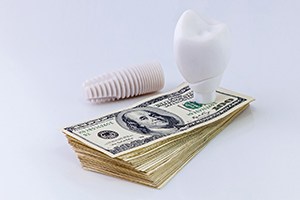 model implant on money representing the cost of dental implants in Northborough 