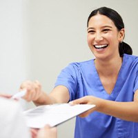 Dental team member handing clipboard to patient
