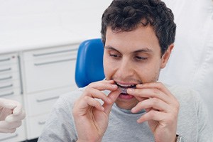 Invisalign patient placing aligner in his mouth