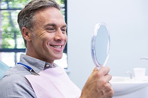 Man in dental chair looking at smile in mirror