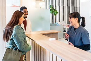 Patients interacting with dental team member at front desk