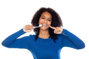 Young woman in blue shirt holding toothbrush and smiling