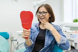 Woman looking in mirror after smile makeover