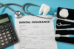 Dental insurance document with calculator and other instruments