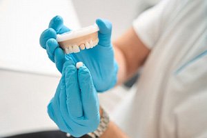 Dental team member using model to demonstrate how dental crowns work