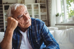 Sad senior man sitting on sofa