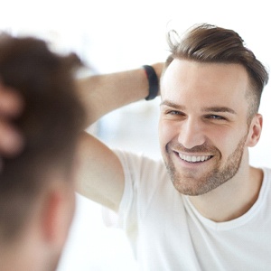 Man admiring results of dental bonding in mirror