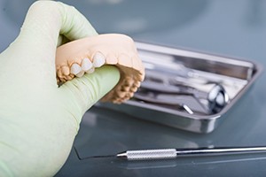 Dental laboratory technician holding model with dental bridge