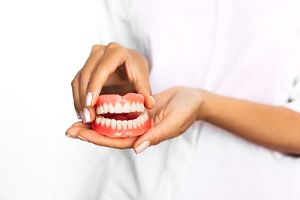 Female dental professional holding full set of dentures