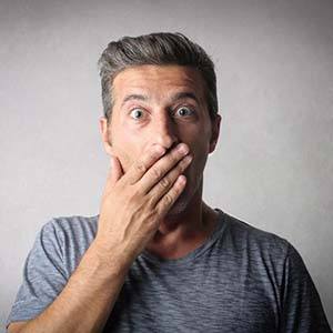 Surprised man covering his mouth should visit Northborough emergency dentist