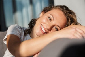 Smiling woman relaxing at home after tooth extraction