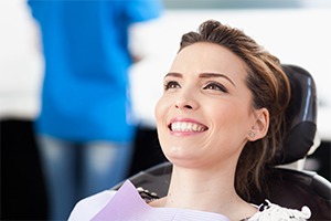 Woman in dental chair smiling after tooth extraction