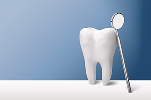 Tooth model and dental mirror against neutral background