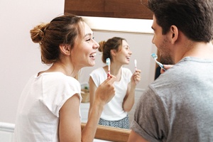 Couple brushing their teeth as part of dental implant care