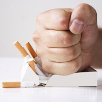Close-up of man’s hand crushing pack of cigarettes