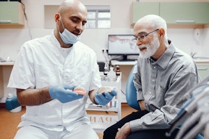 Dentist and senior man discussing procedure for implant dentures