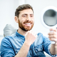 Dental patient admiring his new dental implant restorations