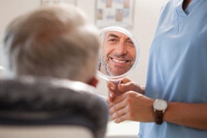 Happy patient admiring his new restorations in mirror