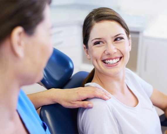 Woman in dental chair smiling at her dentist