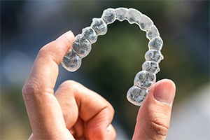 Hand holding up an Invisalign tray