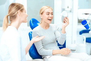 Woman in dental office admiring her new porcelain veneers