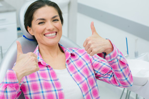Happy dental patient making double thumbs-up gesture