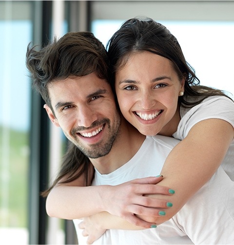 Young man and woman grinning outdoors