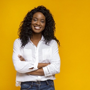 Woman with beautiful teeth smiling confidently against yellow background
