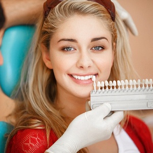 Dentist holding shade guide next to patient’s teeth