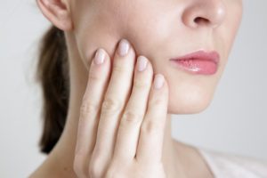 Woman touching jaw, concerned about loose dental implant