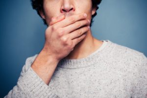 Man covering mouth, wondering if dental implants stain