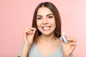 Woman flossing with Invisalign in Northborough against pink background