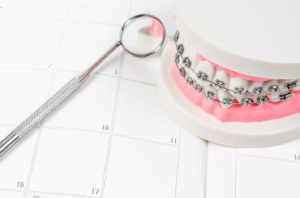 Dental model with braces resting on calendar, representing braces treatment time