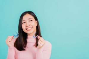 Smiling woman holding two orthodontic retainers